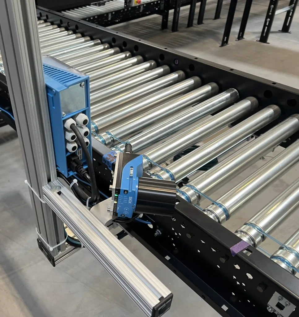 A conveyor system with multiple accessories attached such as o-bands, photo eyes, and scanner.