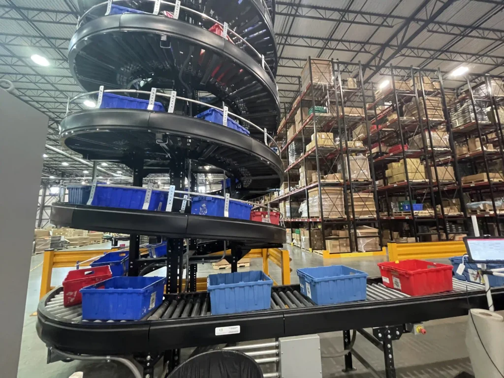 A black conveyor spiral moving bins down in a fulfillment center.