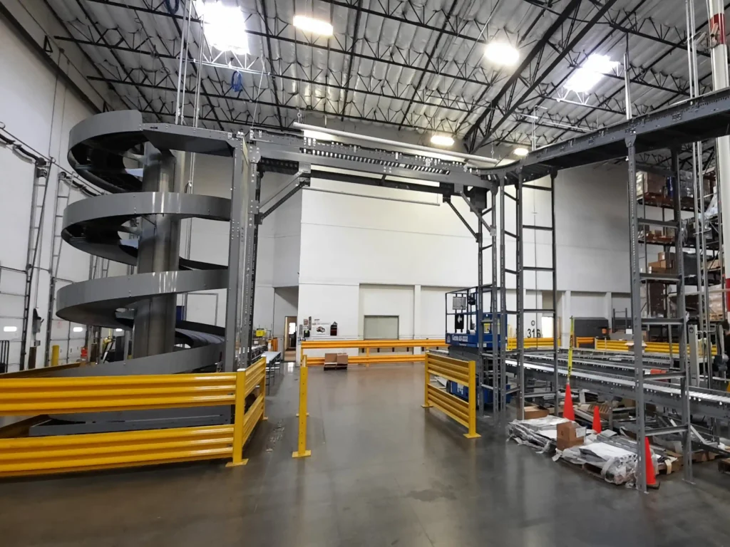 A two-level conveyor system on the right, with one conveyor at 3 feet high and another at 20 feet high. The 20-foot conveyor moves across the middle of the image over a forklift aisle and continues to the left, where it transitions into a spiral conveyor that descends to a 3-foot high conveyor.
