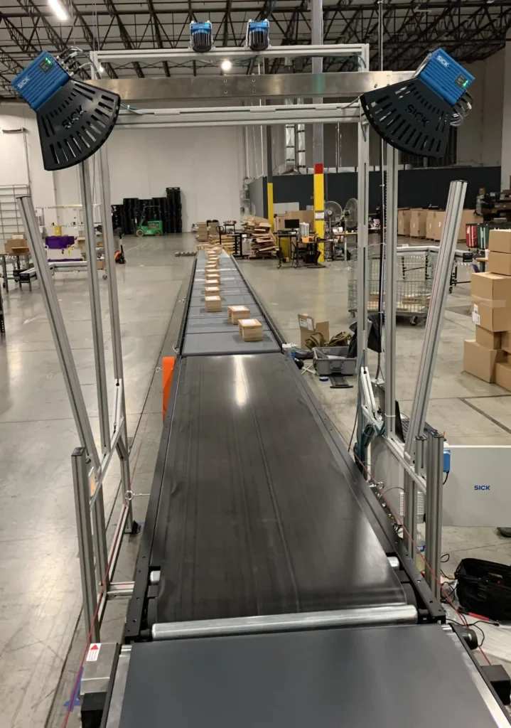 A DWSM conveyor system used for measuring dimensions, capturing weight, scanning barcodes, and generating shipping manifests in a distribution center.